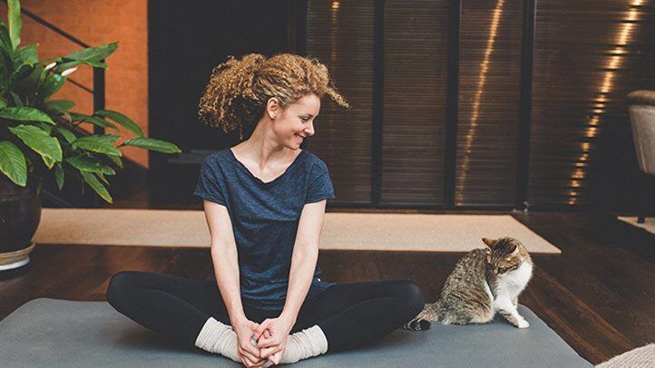 a woman doing yoga with a cat nearby
